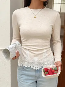 Detail of slim-fit beige knit top with delicate white lace hem and ruched sides