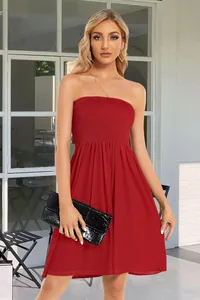 Full view of elegant red strapless smocked dress with black clutch bag