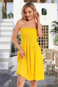 Model wearing a bright yellow strapless smocked tube midi dress in a resort patio setting