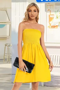 Model wearing a vibrant yellow smocked strapless tube dress in an outdoor setting