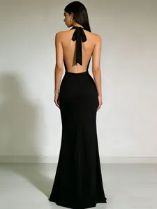 Elegante zwarte avondjurk met halternek en open rug voorzien van een groot strikdetail