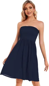 A studio portrait of a woman wearing an elegant navy blue strapless smocked dress