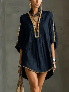 Detail of navy resort dress featuring intricate gold braided trim along the V-neck.
