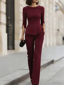 Elegant burgundy professional two-piece suit with asymmetrical top and tailored pants.