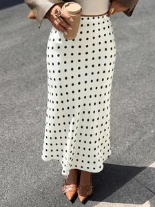 Detailed view of an elegant white polka dot fishtail midi skirt styled with a brown jacket