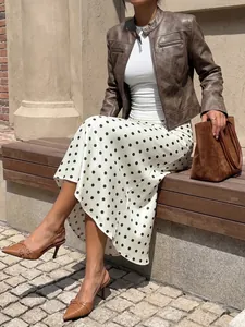Satin polka dot midi skirt paired with brown leather jacket sitting on a wooden bench