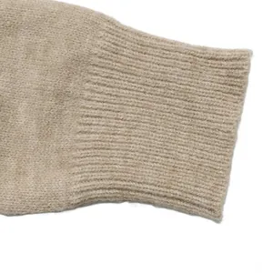 Gros plan du poignet en tricot côtelé sur un pull beige doux avec des détails
