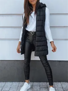 Women's black hooded long puffer vest with white long sleeve top and leather leggings.