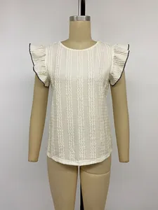 Detailansicht eines weißen Strickoberteils mit strukturierten Rüschenärmeln und schwarzem Rand.