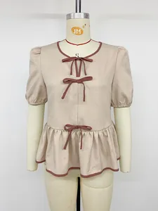 Elegante beige Puffärmelbluse mit kontrastierenden rosa Schleifen und Schößchen-Saum