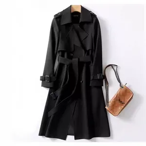 Elegante trench nero di media lunghezza con cintura regolabile e borsa a tracolla marrone