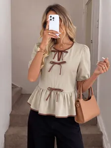 Detailansicht einer eleganten beigen Puffärmelbluse mit braunen Schleifenakzenten.