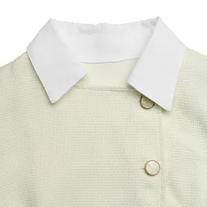 Close-up detail of a cream tweed dress collar with white lapels and pearl buttons.