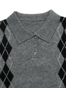 Primo piano di un maglione in maglia a rombi grigio con colletto polo e bottoni.