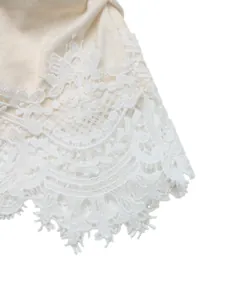Close-up macro view showing the delicate white lace patchwork detail on a cream knit top