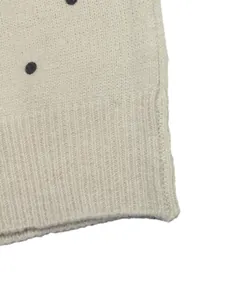 Hochwertiges Makro-Detail eines cremefarbenen Polka-Dot-Strickpullovers mit weichem Rippsaum