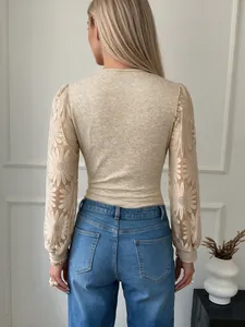 Vista trasera de un body beige de manga larga con encaje floral detallado en las mangas