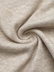 Primer plano del suave tejido de punto beige que muestra la textura y caída.