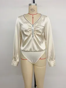 Detail van elegante champagne satijnen bodysuit met lovertjes V-hals en plooien