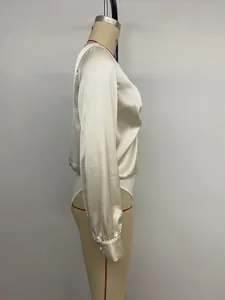 Zijprofiel detail van een elegante champagne satijnen bodysuit met lange mouwen