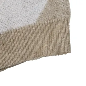 Détail macro du pull en maille argyle douce montrant l'ourlet côtelé et la texture