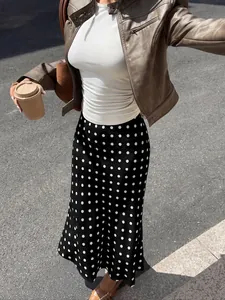High-waisted black midi skirt with white polka dots and fishtail hem for a stylish look