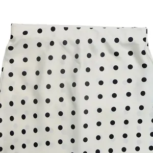 Detail view of the fabric and waistband on a white high waist midi skirt with black polka dots