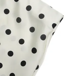 Close-up of white fabric with elegant black polka dots and fine stitching detail