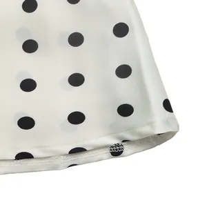 Close-up of black polka dot pattern and hemline stitching on white satin fabric detail