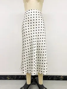Elegant high-waisted white midi skirt with black polka dots on a store mannequin.