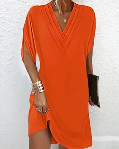 Gros plan d'une robe orange vif avec col en V et détails plissés élégants.