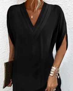 Détail d'une robe noire élégante à col en V avec des plis et des manches chauve-souris.