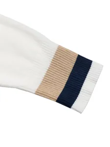 Detailed view of ribbed knit cuff with tan and navy stripes on casual white sweater.