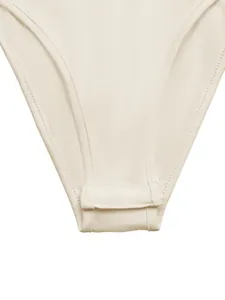 Gedetailleerd overzicht van de functionele drukknoopsluiting op een beige satijnen bodysuit