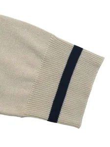 Detailed view of a beige knit sweater sleeve featuring a navy blue contrast stripe
