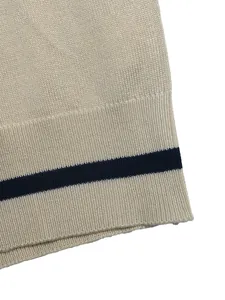 Close-up of knit sweater hem showing beige texture and navy blue stripe detail