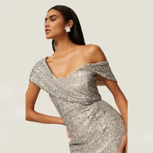 Gros plan sur les détails des paillettes argentées et l'encolure asymétrique de la robe