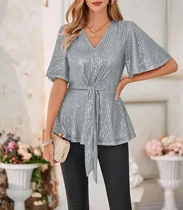 Detail of silver V-neck sequin top with flare sleeves and tie-waist design.