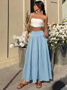 Model wearing light blue tiered maxi skirt with smocked high waist and textured fabric