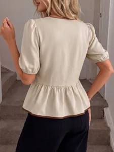 Rückansicht einer cremefarbenen Schößchenbluse mit kontrastierenden braunen Details.