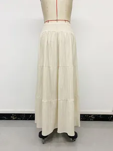 Detail view showing the pleated texture of a cream high-waisted smocked maxi skirt on a mannequin.