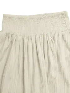 Detailed macro view showing smocked high waistline and crinkle fabric texture of beige skirt