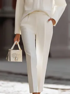 Vista dettagliata dei chic pantaloni bianchi da ufficio con borsa coordinata
