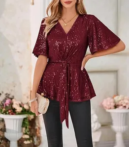 Elegant detail of a burgundy sequin V-neck top with flutter sleeves and waist tie