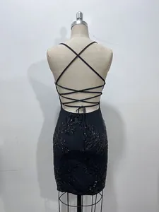Détail du design dos nu et des bretelles croisées sur une robe de soirée noire à paillettes.