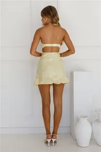 Detailed back view of a sexy yellow tube top mini dress featuring floral texture and ruffles