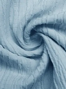 Macro view of light blue smocked textured fabric showing fine ribbed detail and soft drape
