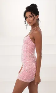 Side view of a shimmering pink sequined mini bodycon dress with spaghetti straps.