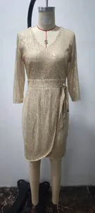 Sparkling gold sequin long sleeve wrap dress with waist tie displayed on a mannequin.