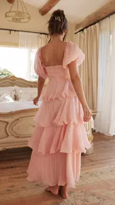 Vista posterior detallada de un elegante vestido largo rosa con capas y mangas abullonadas